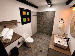 A bathroom with a toilet, a shower, a sink with a marble countertop, and a towel rack.