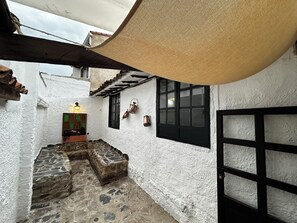 A courtyard with stone steps, a wooden bench, a lantern, and a black gate.