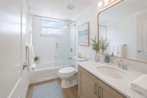 A modern bathroom with a bathtub, toilet, and sink. - Gaslamp District Gem Walk to Dining (San Diego)