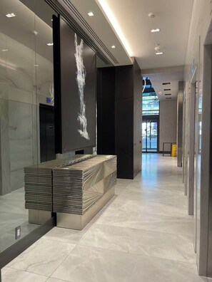 A modern lobby with a reception desk, glass walls, and a digital sign.