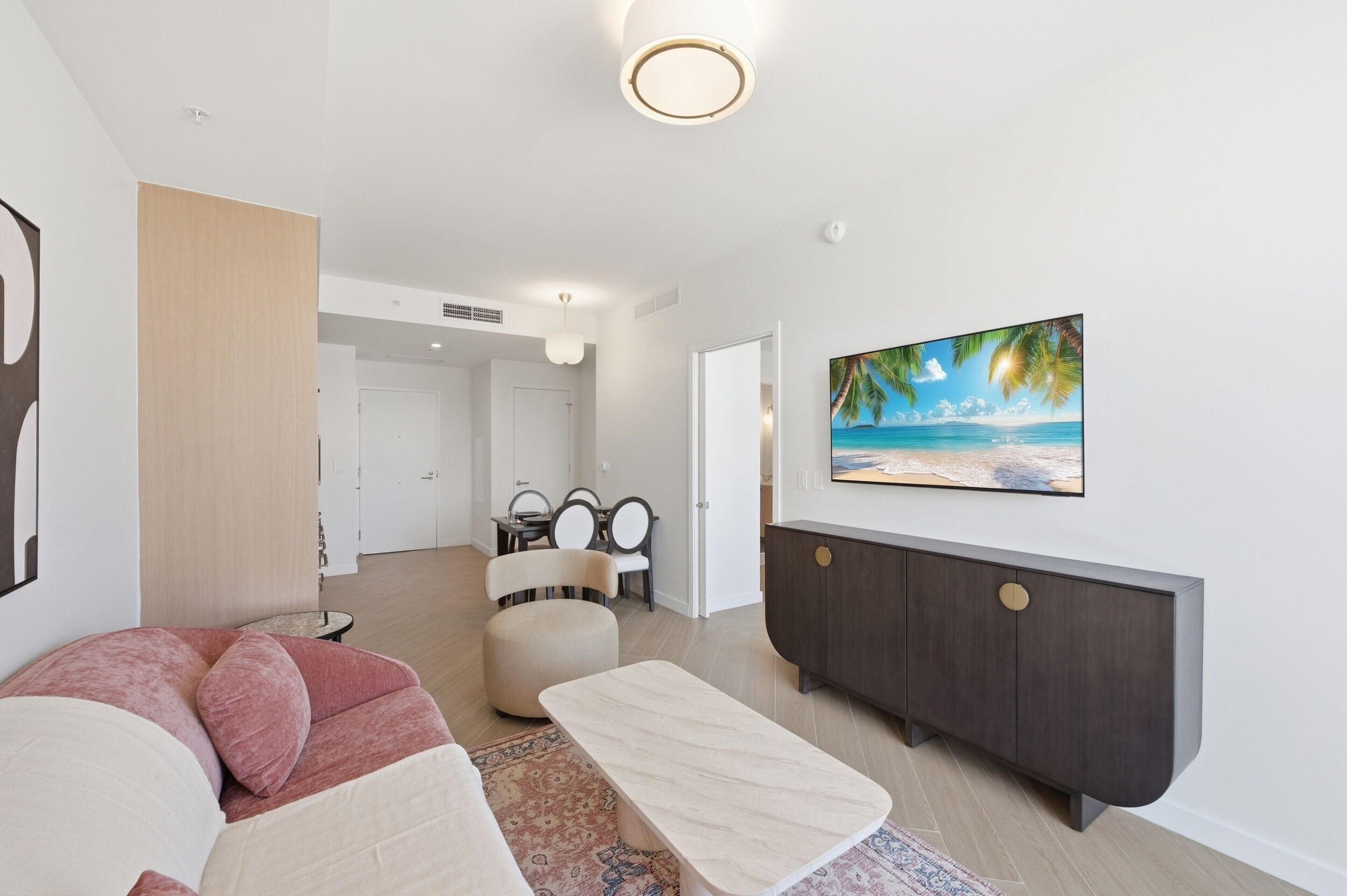 Uma sala de estar moderna com sofá, mesa de centro, aparador de madeira escura e uma pintura de uma cena de praia.