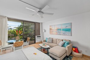 Ein modernes Hotelzimmer mit Balkon, Deckenventilator, Sofa, Esstisch und Meerblick.
