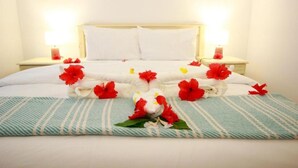 Une chambre d’hôtel avec un lit, des oreillers, des tables de chevet et un arrangement floral.