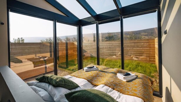 Ein Schlafzimmer mit einem großen Bett, einem Oberlicht und Blick ins Freie.