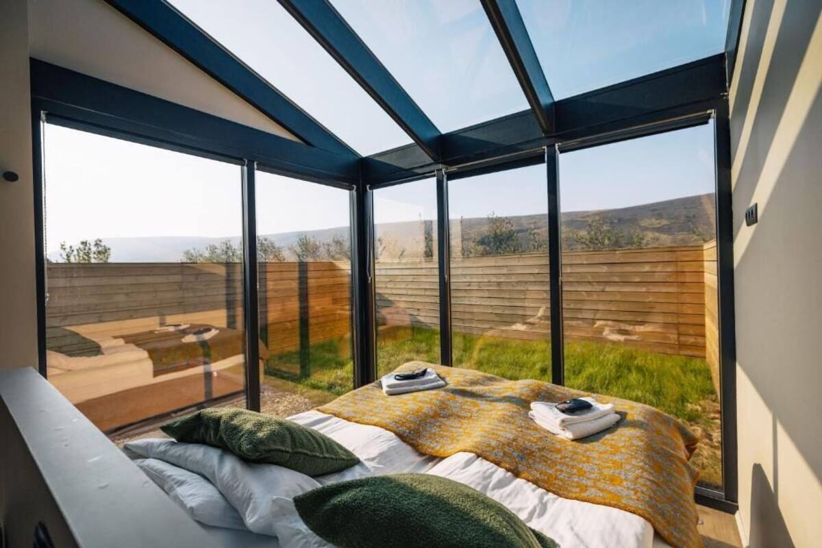 A bedroom with a large bed, a skylight, and a view of the outdoors.