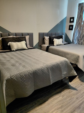 Two beds with headboards, a wooden floor, and a wall with a geometric pattern.