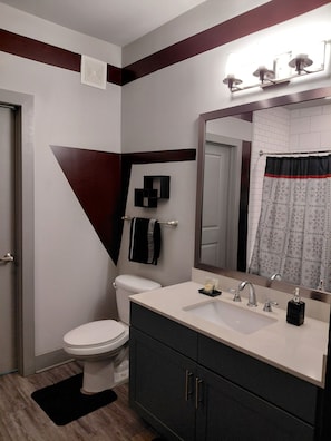 A bathroom with a toilet, a sink, a mirror, and a shower curtain.
