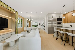 Eine moderne Küche mit Einbauofen, einem Edelstahl-Kühlschrank und einer Bar mit Hockern.