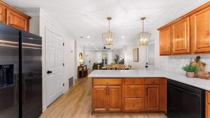 A modern kitchen with wooden cabinets, a stainless steel refrigerator, and a central island. - The Pinewood · Dog-Friendly 30A Home for 8 (Santa Rosa Beach)
