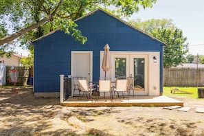 Une maison bleue avec une terrasse, une porte et une fenêtre.
