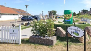 Eingang eines Golfplatzes mit einem Schild für 'Adventure Golf' und einer großen Werbung für 'Faxen Konni'.