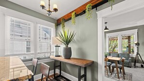 Un comedor con una mesa de madera, sillas, una planta en maceta y vistas al exterior.