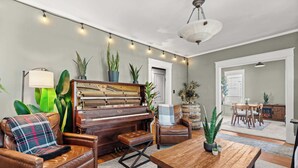 Un salón con piano, sillón de cuero, reposapiés y mesa de centro de madera.