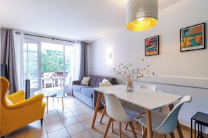Ein modernes Wohnzimmer mit einer Couch, einem gelben Sessel, einem Esstisch und Stühlen.