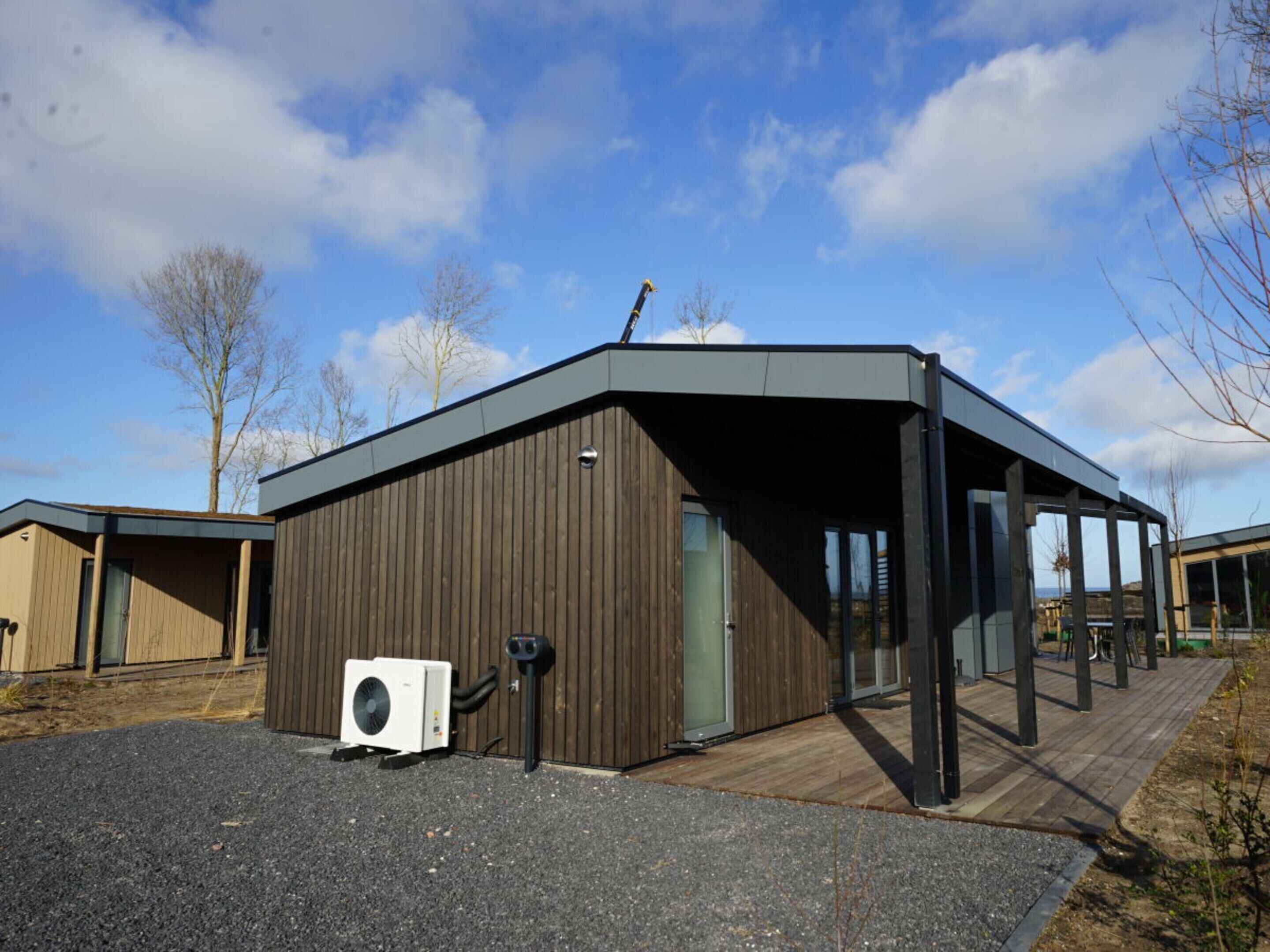 A modern building with a sloped roof, large windows, and a wooden exterior.