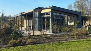 A modern building with large glass windows, a flat roof, and a surrounding grassy area.