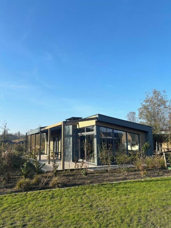 Een modern gebouw met grote glasramen, een plat dak en een omliggend gazon.