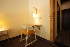 Un racó amb una taula petita, una cadira, una làmpada de paret i una porta.