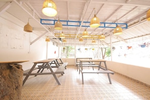 A room with tables and benches, hanging wicker lamps, and a patterned floor. - Premium Dome With Hill and River Viewhotel Ribera (Dehradun)