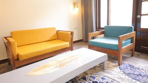 Una habitación con un sofá amarillo, un sillón azul y una mesa de centro blanca.