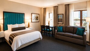 Quarto de hotel com uma cama grande, um sofá, uma escrivaninha e duas cadeiras.