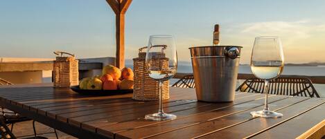 A wooden table with two wine glasses, a metal bucket, and wicker baskets containing fruits.