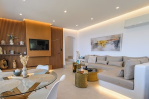 A modern living room with a sofa, coffee table, and TV. There is a staircase leading to another level.