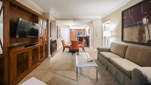 A living room with a TV, wooden cabinets, a glass coffee table, and a sofa. - 1BD/2BA • Balcony • No Resort Fee • Free Parking E25D1 (Las Vegas)
