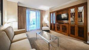 A hotel room with a sofa, armchair, TV, and a glass coffee table. - 1BD/2BA • Balcony • No Resort Fee • Free Parking E25D1 (Las Vegas)