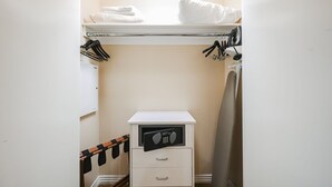 A compact walk-in closet with a hanging rack, a small storage unit, and a mirror.