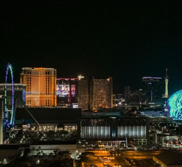 A cityscape at night with illuminated buildings, including a prominent tower and a large dome structure. - PH Floor Studio • Strip View • Balcony • No Resort Fee D29P3 (Las Vegas)