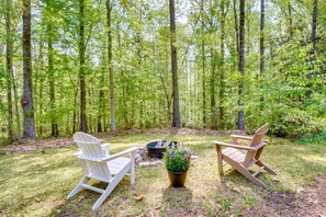 A forested area with two Adirondack chairs and a fire pit. - Tranquil 1-bedroom apartment with AC in charming Toccoa (Toccoa)