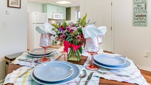 A dining table set with blue plates, wine glasses, and silverware, a vase with flowers, and a framed quote on the wall. - Tranquil 1-bedroom apartment with AC in charming Toccoa (Toccoa)