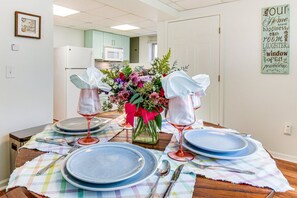 A dining table set with blue plates, wine glasses, and silverware, a vase with flowers, and a framed quote on the wall. - Tranquil 1-bedroom apartment with AC in charming Toccoa (Toccoa)