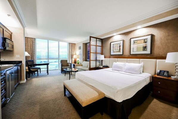A hotel room with a bed, a desk, a chair, a bench, a kitchenette, and a large window with a view. - Strip View Studio • No Resort Fee • Free Parking B18P1 (Las Vegas)