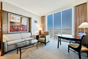 A hotel room with a large window, a sofa, a chair, a small table, and a lamp. - SVS: Sphere Strip View Studio | Signature at MGM (Las Vegas)