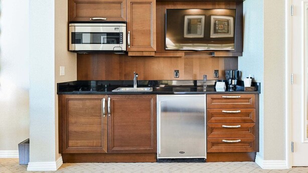 A compact kitchen with a microwave, dishwasher, and wooden cabinets. - SVS: PH Floor Studio | Signature at MGM (Las Vegas)