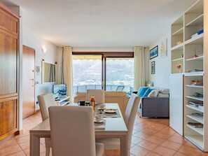 Un comedor con mesa, sillas y vistas a montañas nevadas a través de amplios ventanales.