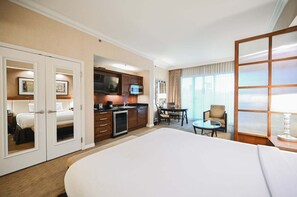 A hotel room with a large bed, a kitchenette, a dining area, and a view of the outdoors. - SVS: PH Floor Strip View Balcony | Signature at MGM (Las Vegas)