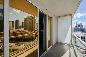 A balcony with a cityscape view, a sliding glass door, and a clear sky. - SVS: Strip View Balcony | Signature at MGM (Las Vegas)