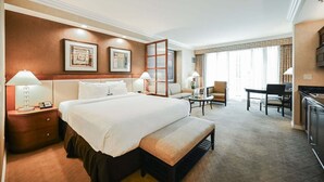 A hotel room with a large bed, bedside tables, a desk, a chair, and a view of the outdoors. - SVS: Strip View Balcony | Signature at MGM (Las Vegas)