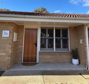 A residential building with a tiled roof, a wooden door, and a window with horizontal blinds.