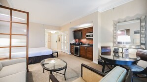 A hotel room with a bed, a seating area with a glass table, a kitchenette, and a large mirror. - SVS: PH Floor Strip View Balcony | Signature at MGM (Las Vegas)