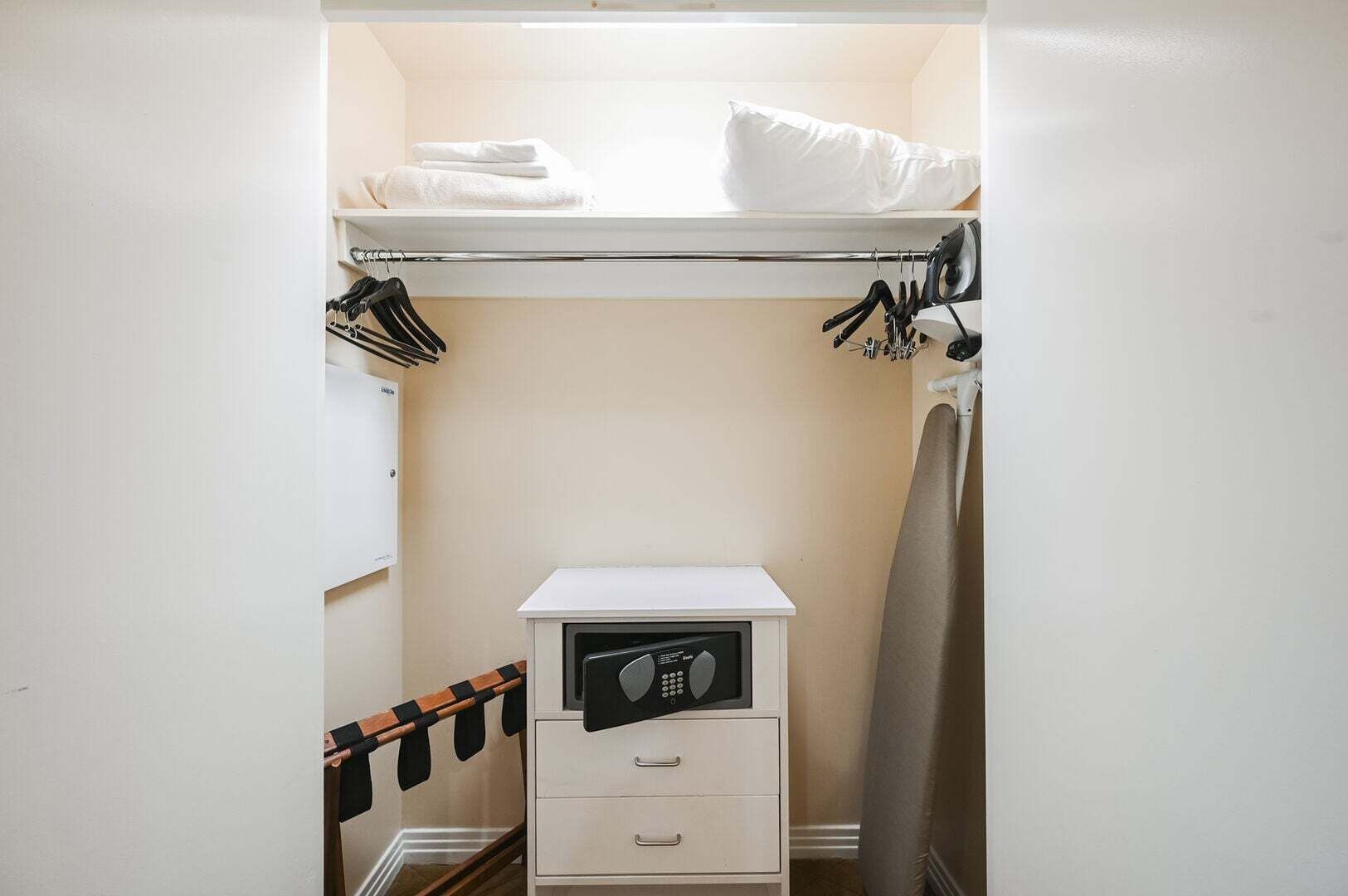 A compact storage closet with a hanging rack, a small drawer unit, and a built-in heater.