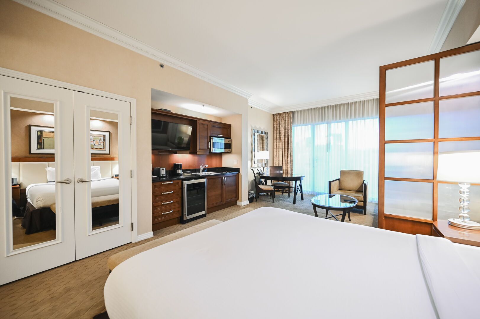 Habitación de hotel con una cama grande, kitchenette, comedor y vistas al exterior.
