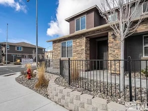 A building with stone facade, a red fire hydrant, and a black metal fence. - 2 BR Layout with Bonus Room • Quiet + Parking (Carson City)