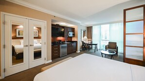Ein Hotelzimmer mit Bett, einer Küchenzeile, einem Essbereich und Blick auf die Stadt.