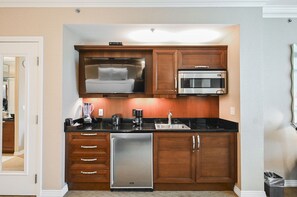 A compact kitchen with wooden cabinets, a built-in microwave, a refrigerator, and a coffee maker. - Studio • No Resort Fee • Free Parking A3B1 (Las Vegas)