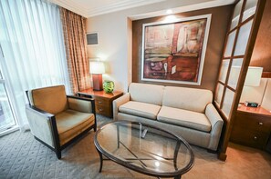 A hotel room with a sofa, armchair, glass coffee table, and a painting on the wall. - Studio • No Resort Fee • Free Parking A3B1 (Las Vegas)