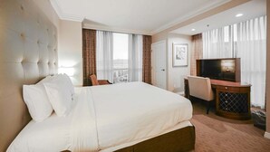 Una camera d'albergo con un letto grande, una TV, una scrivania e una sedia.